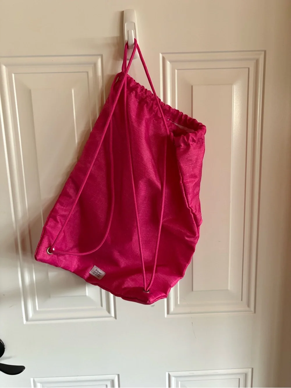 Cute personalized drawstring backpack in a vibrant pink fabric, letter L